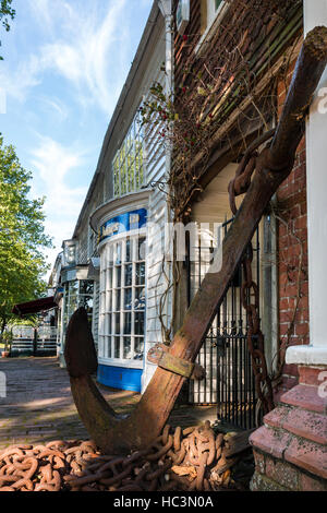 England, Tenterden. Breite Low Angle View entlang Gebäude in der High Street. Vordergrund, Rostige Anker außerhalb Lagerträger Haus mit anderen Gebäuden entlang der Straße. Stockfoto