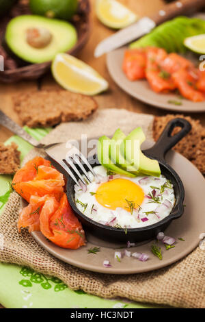 Spiegelei, Avocado und geräucherter Lachs in der Pfanne serviert zum Frühstück Stockfoto