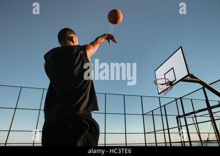 Porträt eines Basketball-Spielers unter einem Sprungwurf auf einem Basketballfeld im freien Stockfoto