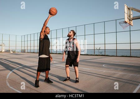 In voller Länge Portrait von zwei jungen Männern, die Basketball spielen auf dem Spielplatz Stockfoto