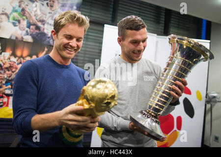 Köln, Deutschland. 7. Dezember 2016. Formel 1 Weltmeister Nico Rosberg (L) und der ehemaligen Nationalmannschaft Fußballspieler Lukas Podolski stellen mit dem Pokal der Formel-1-WM und die Fußball-WM am Flughafen in Köln, Deutschland, 7. Dezember 2016. Foto: Rolf Vennenbernd/Dpa/Alamy Live News Stockfoto