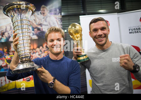 Köln, Deutschland. 7. Dezember 2016. Formel 1 Weltmeister Nico Rosberg (L) und der ehemaligen Nationalmannschaft Fußballspieler Lukas Podolski stellen mit dem Pokal der Formel-1-WM und die Fußball-WM am Flughafen in Köln, Deutschland, 7. Dezember 2016. Foto: Rolf Vennenbernd/Dpa/Alamy Live News Stockfoto