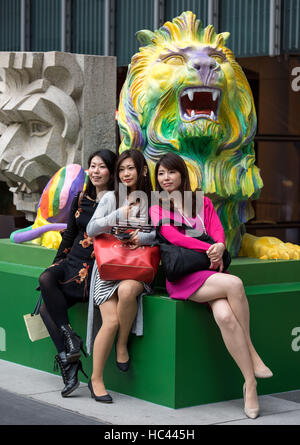 Hong Kong, Hong Kong SAR, China. 6. Dezember 2016. Japanische Touristen posieren mit der Regenbogen-Löwen. Regenbogen stolz Löwen werden zugunsten von LGBTI Menschen am Hauptsitz HSBC in Central Hong Kong angezeigt. Ihre Anzeige hat Kontroverse verursacht und aufgefordert eine Petition für deren Beseitigung sowie Bedrohungen durch Kunden, ihre Konten zu schließen. Die Löwen sind Repliken in Regenbogenfarben von Stephen und Stitt, die Bank ikonischen Löwen, vor das Hauptgebäude. Die Statuen, entworfen von dem lokalen LGBT-Künstler Michael Lam, stolz dar, die Einheit in der Vielfalt, mit Stephen in Streifen (Bild gemalt Stockfoto