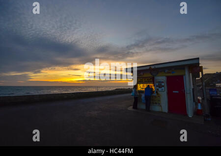 West Bay, Dorset, UK.  7. Dezember 2016. Die Sonne geht hinter dem Eis Kiosk West Bay in Dorset nach einem Tag bewölkt und diesig Sonnenschein. Foto von Graham Hunt/Alamy Live-Nachrichten Stockfoto