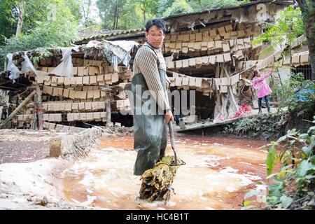 (161208)--CHONGQING, 8. Dezember 2016 (Xinhua)--Li Gaoqiang zieht getaucht Bambus aus Kalk Pool in Xinglong Stadt, Südwest-China Chongqing, 7. Dezember 2016. LIS-Familie, Leben in Xinglong Stadt Chongqing hat das traditionelle Handwerk der Herstellung von "Tuhuo" Papier über fünf Generationen überliefert. "Tuhuo" Papier, Bambus wächst in lokalen Bereichen erfordert hohen Standard der Techniken durch alle Verarbeitungsstufen. Allerdings ist mit hoher Arbeitsintensität, schlechten Verkaufszahlen und niedrigen Renditen, das Handwerk nur wenige junge Menschen, erbte die trieb der Regierung, es als eine Tourismus-Jubiläumsfeierlichkeiten zu entwickeln Stockfoto