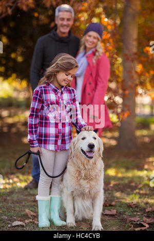 Mädchen streicheln Hund während die Eltern im park Stockfoto
