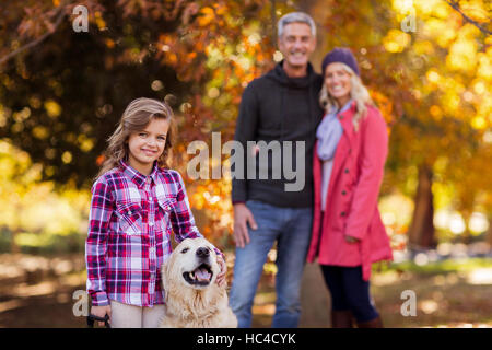 Mädchen mit Hund, während die Eltern stehen im park Stockfoto