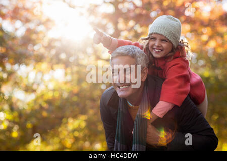 Huckepack Tochter Vater gegen Herbst Bäume Stockfoto