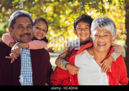 Glückliche Großeltern Huckepack Enkel im park Stockfoto