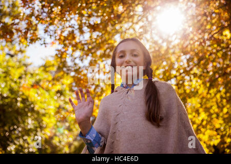 Niedrigen Winkel Blick lächelnder winkenden Hand Mädchen im park Stockfoto
