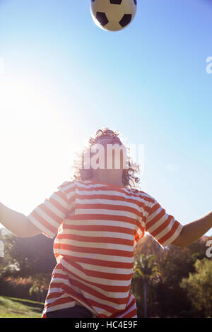 Niedrigen Winkel Ansicht der junge spielt mit Fußball im park Stockfoto