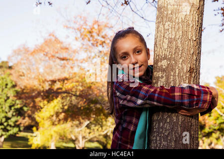 Porträt von lächelndes Mädchen Baum umarmen Stockfoto