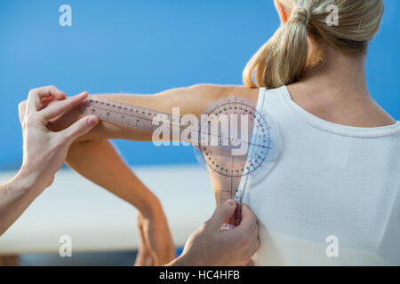 Männlichen Therapeuten Messung von weiblichen Patienten Schulter mit Winkelmesser Stockfoto