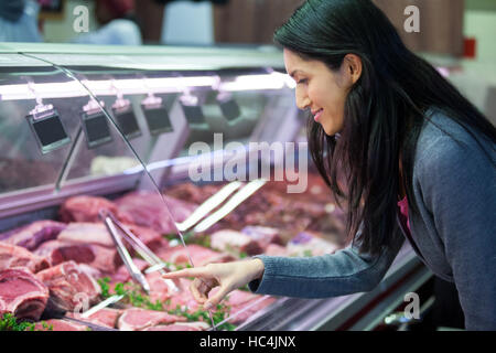 Frau zeigt auf Fleisch im display Stockfoto