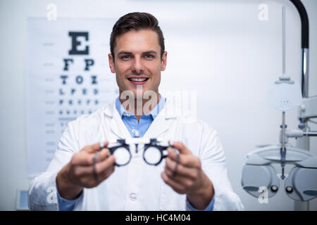 Lächelnd hält Messbrille Augenarzt Stockfoto