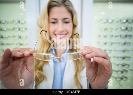Lächelnde weibliche Optiker Brillen halten Stockfoto