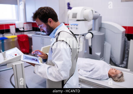 Arzt mit digital-Tablette und Patienten liegen auf X-Ray Maschine Stockfoto