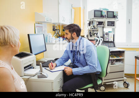 Arzt in Zwischenablage beim betrachten Computer schreiben Stockfoto