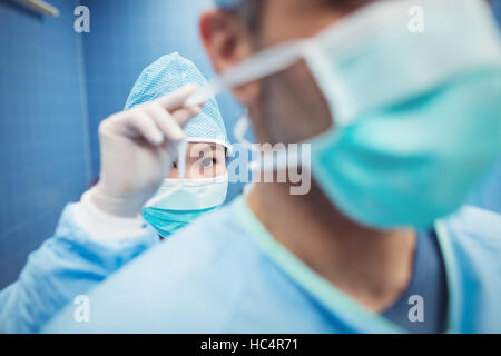 Krankenschwester hilft ein Chirurg im OP-Maske verknüpfen Stockfoto