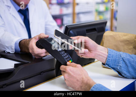 Kunde die Zahlung durch Smartphone in Zahlung terminal Stockfoto