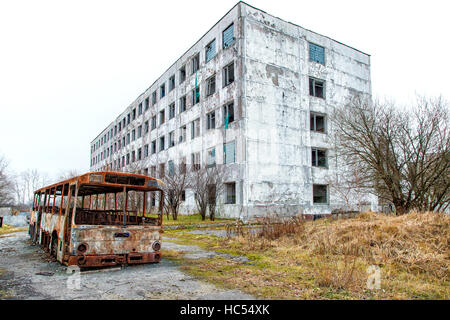 alten verlassenen Hochhaus mit gebrannten Bus an düsteren, kalten Herbsttag Stockfoto