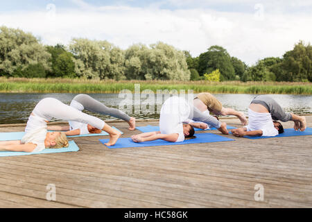 Menschen, die Yoga im Pflug-Pose auf Matte im freien Stockfoto