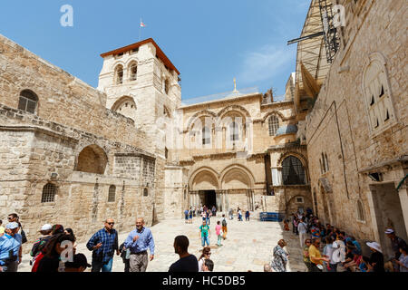 JERUSALEM, ISRAEL - 6. April 2016: Touristen und Pigrims gehen und sitzen auf einem Platz am Eingang der Kirche des Heiligen Grabes in Jerusalem auf Stockfoto