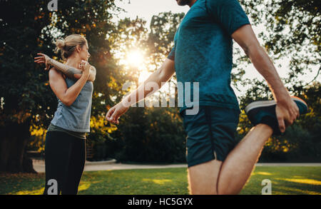 Aufnahme des jungen Mann und Frau, die stretching-Übung im Park zu tun. Junges Paar Aufwärmen für Morgengymnastik. Stockfoto