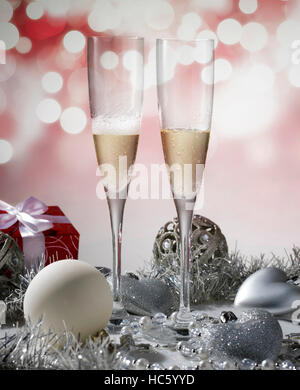 zwei Gläser Champagner für Weihnachtsfeier mit roter Dekoration und Geschenk Stockfoto