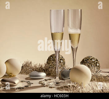 Zwei Gläser mit Champagner, Geschenk-Boxen und Weihnachtsschmuck auf einem gelben Hintergrund mit Lichtern von Garland. Weihnachten und Neujahr. Stockfoto