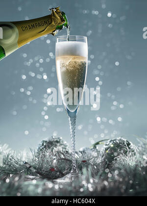 strömenden Champagner ins Glas auf einem blauen Hintergrund Weihnachten Stockfoto