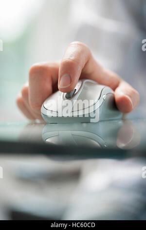 Mann mit seinen Fingern um zu steuern, eine schnurlose Maus auf Glastisch Stockfoto