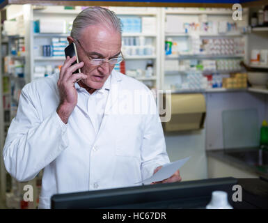 Telefonieren mit Handy während der Überprüfung Rezept Apotheker Stockfoto