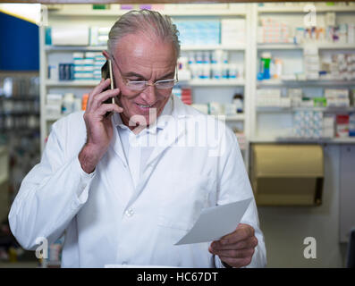 Telefonieren mit Handy während der Überprüfung Rezept Apotheker Stockfoto