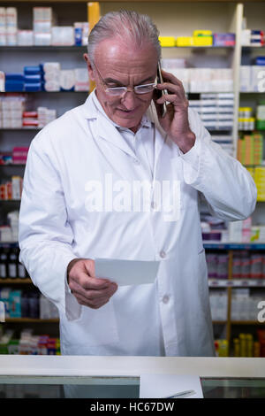 Telefonieren mit Handy während der Überprüfung Rezept Apotheker Stockfoto