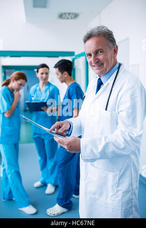 Porträt von lächelnden Arzt stehend mit Röntgen-Bericht im Korridor Stockfoto