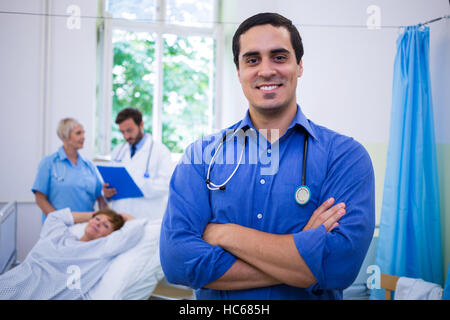 Lächelnde Arzt stehend mit Arme gekreuzt im Krankenhaus Stockfoto