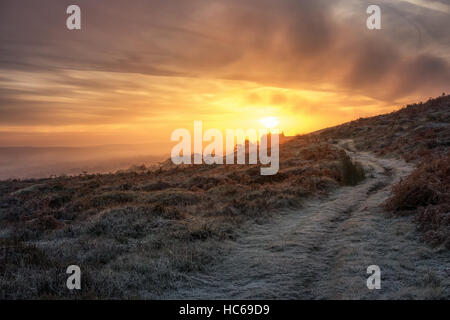 Winter ramble auf frostigen Pfad: Landhaus auf einem Hügel geniessen einen schönen dramatischer Sonnenaufgang über dem Nebel im Tal hängen, Wharfedale, England Stockfoto