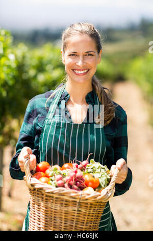 Porträt von glücklich Bäuerin hält einen Korb mit Gemüse Stockfoto