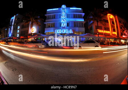 Reihe von Art déco-Hotels, die in der Nacht mit Neonleuchten, einschließlich Colony Hotel, mit Fahrzeugen, die Verwischung von mit zeitgesteuerter Aufnahme, am Strand von South Beach, Miami, USA. Stockfoto