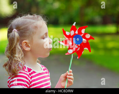 Hübsches kleines Mädchen in Sommertag hält Windmühle in der hand Stockfoto