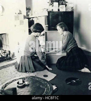 Historisches Archiv Bild zweier junger Frauen, die Datensätze auf dem Plattenspieler anhören. c1960s Stockfoto