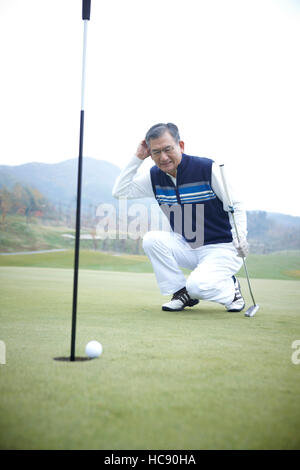 Alte männliche Golfer sitzen Stirnrunzeln sein Gesicht im Feld Stockfoto