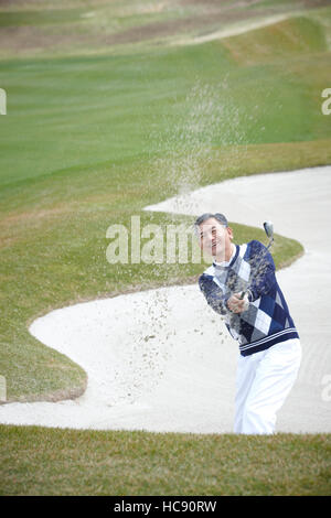 Lächelnde männlichen Golfer halten einen Club im Feld Stockfoto
