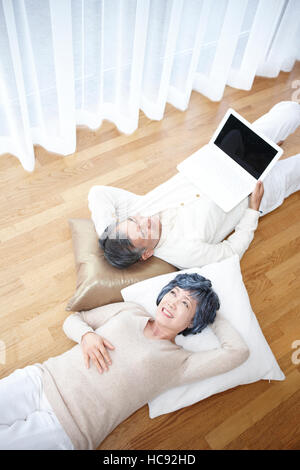 Älteres Paar mit Notebook drinnen ruht lächelnd Stockfoto