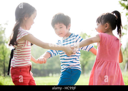 Drei lachende Kinder spielen im Feld Stockfoto