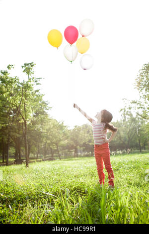 Seitenansicht der Mädchen mit Luftballons Nachschlagen im Feld stehen Stockfoto