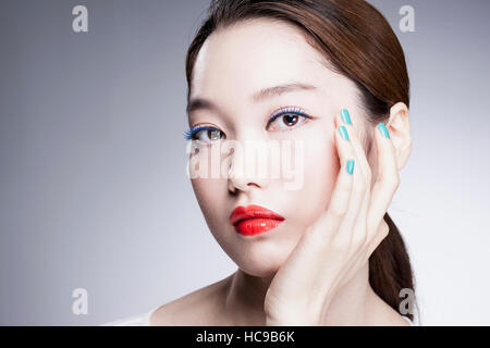 Porträt der jungen Koreanerin mit roten Lippen und blauen Nägeln Stockfoto