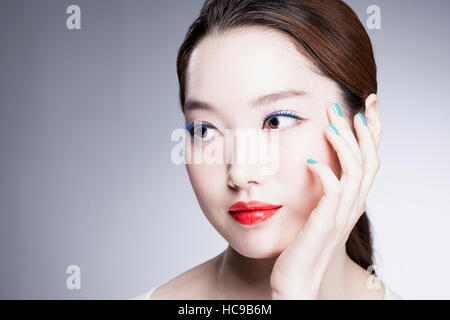 Porträt der jungen Koreanerin mit roten Lippen und blauen Nägeln Stockfoto