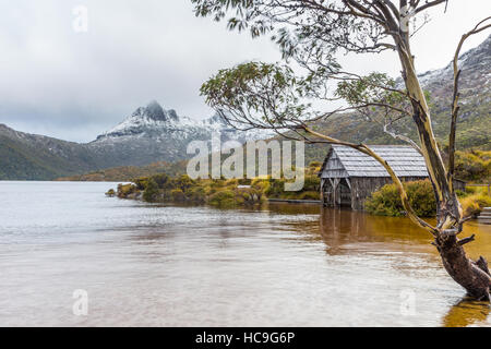 Das Bootshaus am Dove Lake in Cradle Mountain NP (Tasmanien, Australien) mit schneebedeckten Gipfeln des Cradle Mountain im Hintergrund Stockfoto